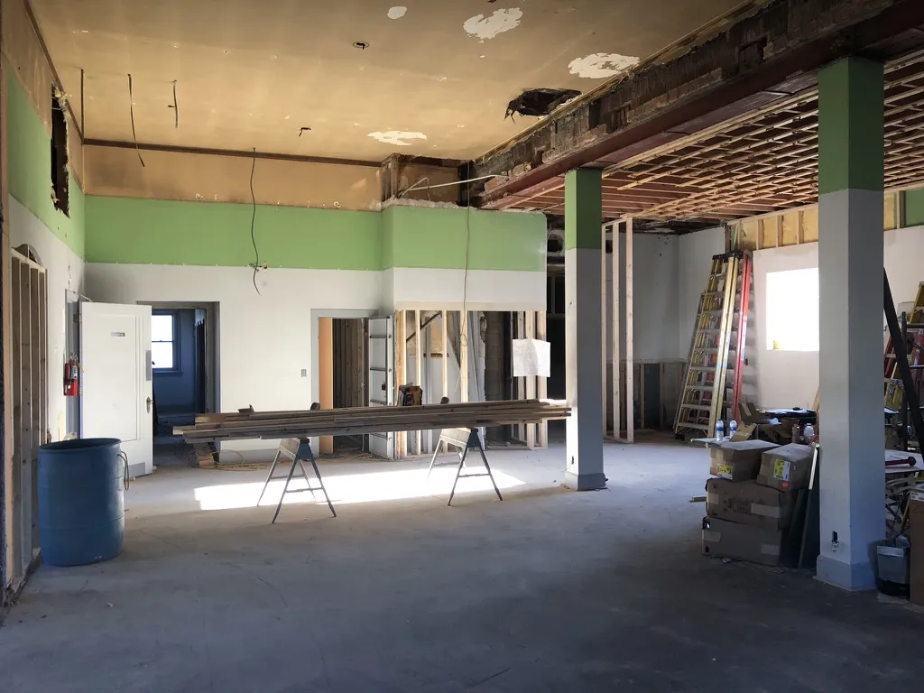The main office floor opened up with framing, ladders and a green-painted wall band