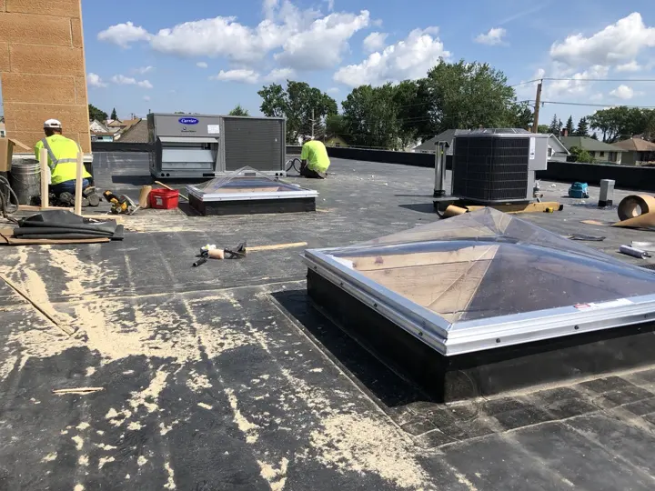 Roofers working around new skylights and rooftop heating and cooling units