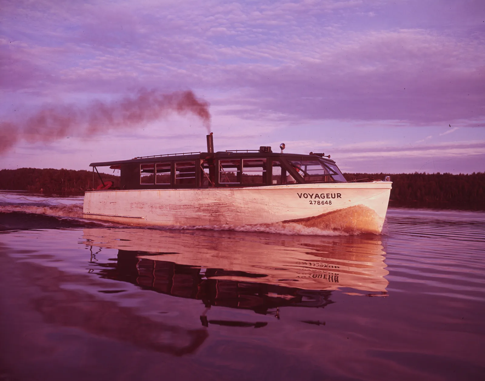 The tour boat Voyageur cruising on a lake at sunset