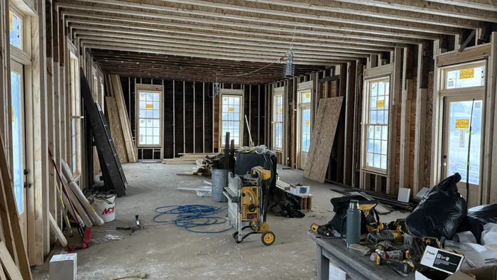 The framed interior with tall new Marvin windows and doors and tools on the floor