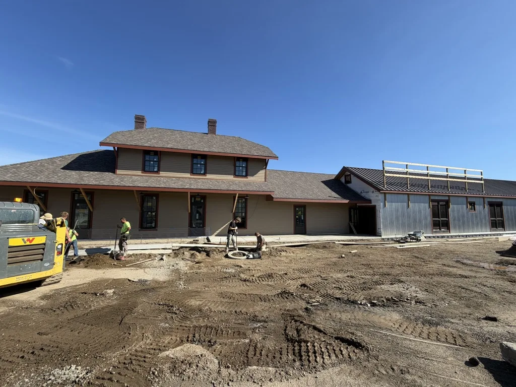 Crews grading the lot and setting drains in front of the finished depot and freight wing
