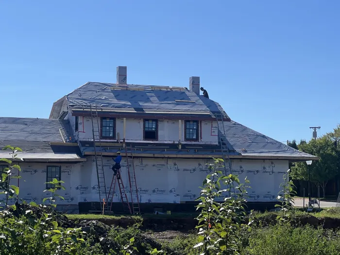 Crews on ladders and the roof of the two-story section, with new windows installed