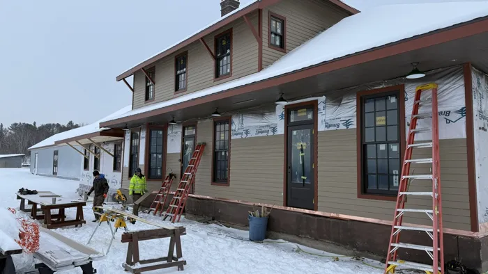Crew members cutting siding outside the depot on a snowy day