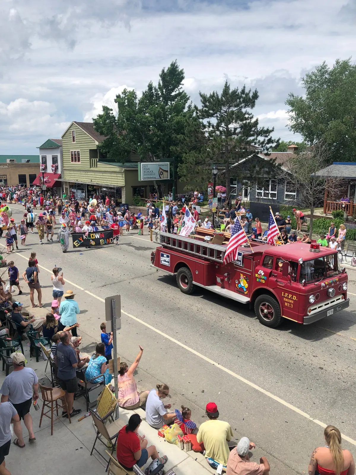 Crowds line Sheridan Street for an Ely parade as the Ely Klown Band and a vintage red fire engine roll past