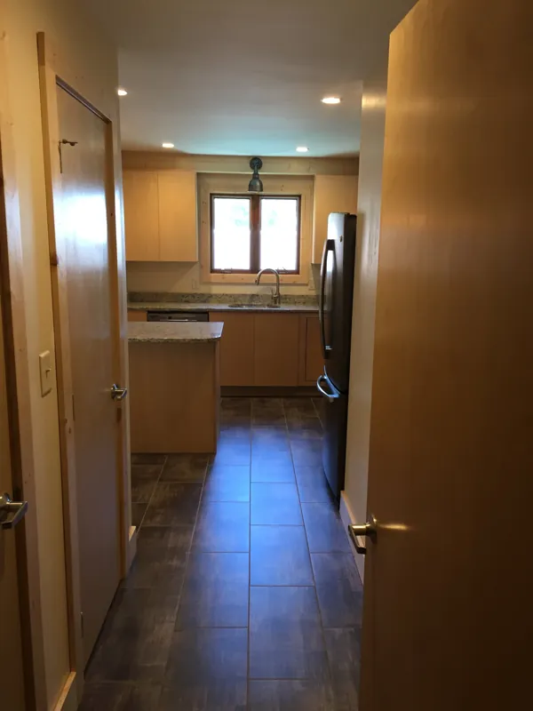 A hallway with tile floors leading to a kitchen