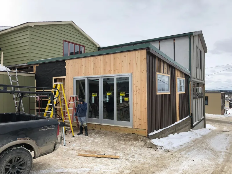 The new studio addition with wood siding and glass doors, with snow on the ground