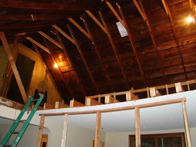 The old roof rafters exposed above new framing