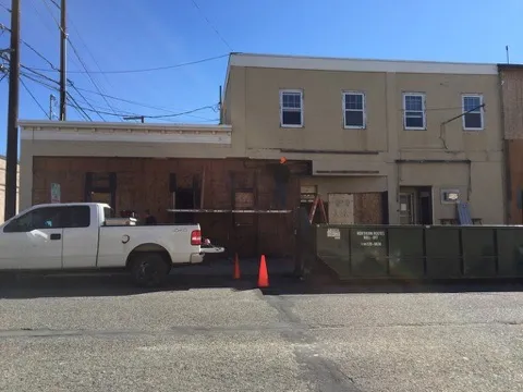The First Avenue storefronts boarded up with a dumpster at the curb