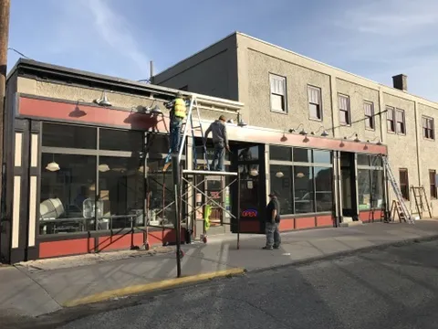 Crew on ladders adding red trim and lights to the First Avenue storefronts