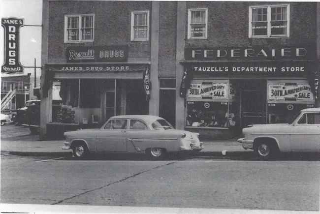 James Drug Store with its Rexall Drugs sign beside Tauzell’s Federated Department Store and its 30th Anniversary Sale, with 1950s cars parked out front