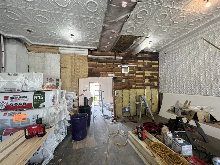 The back wall opened up to old boards and insulation, with insulation bags stacked nearby