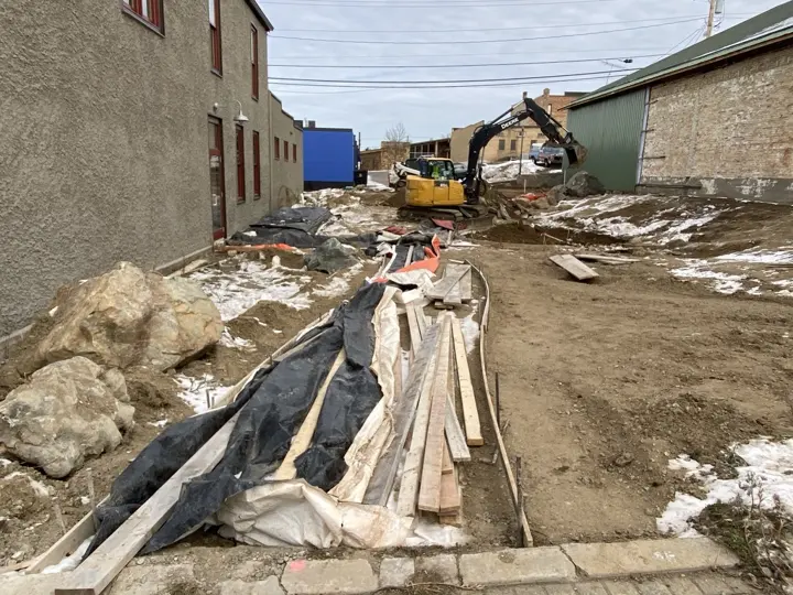 Forms and plastic laid out for the paths with an excavator working beyond