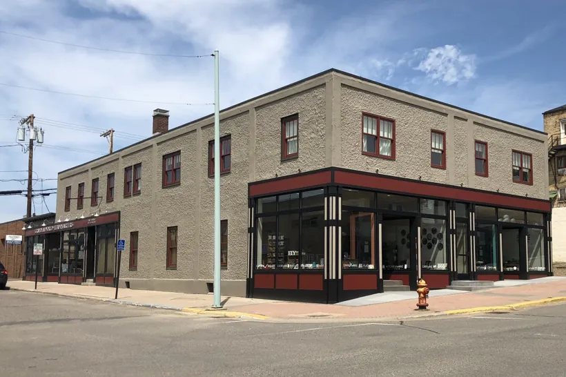 The restored stucco building today with red-trimmed windows and new storefronts