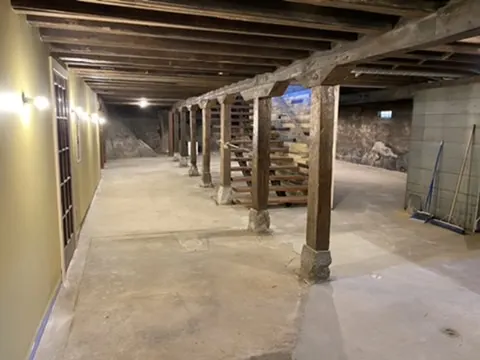 The finished lower level with timber posts, stone walls and wall sconces
