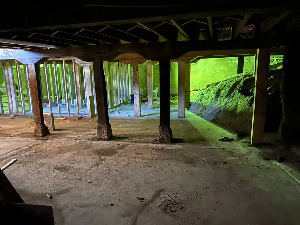 The lower level before, with timber posts on stone footings and new framing beyond