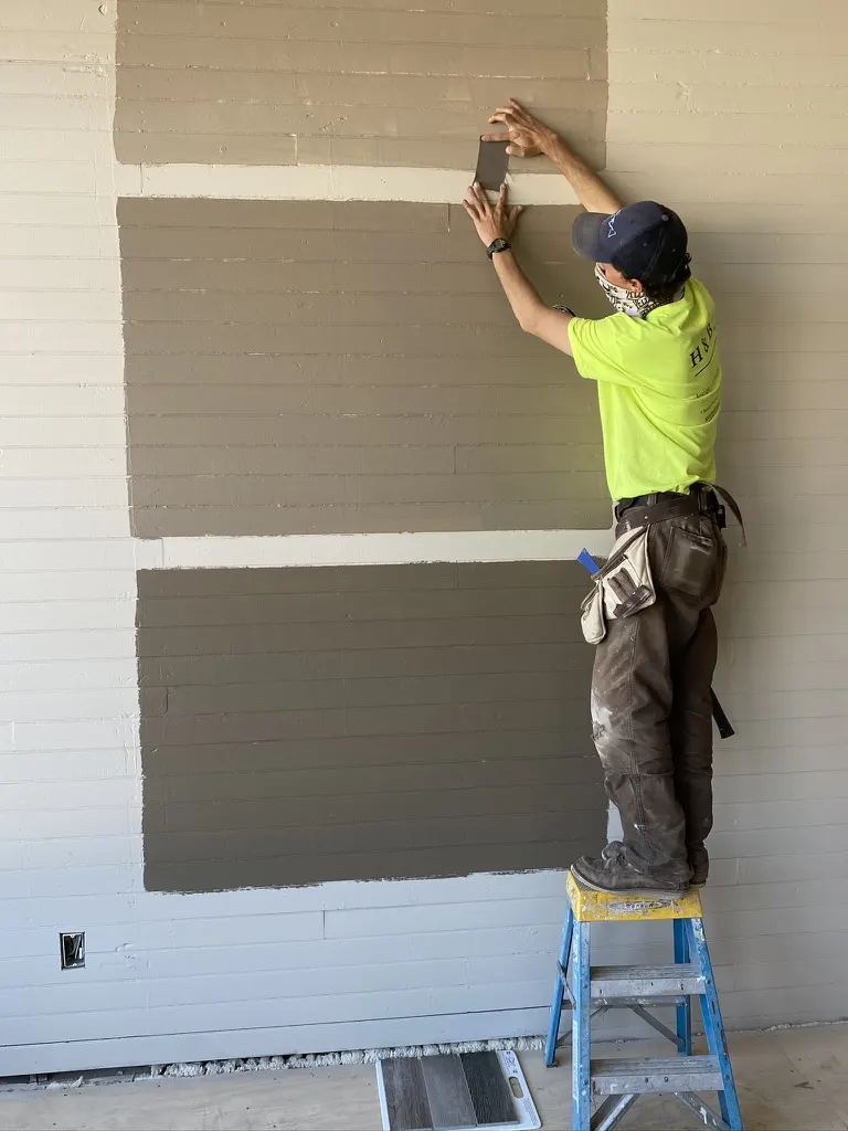 A painter comparing color swatches on the beadboard wall