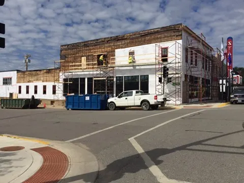 The corner wrapped and scaffolded with new storefront glass below