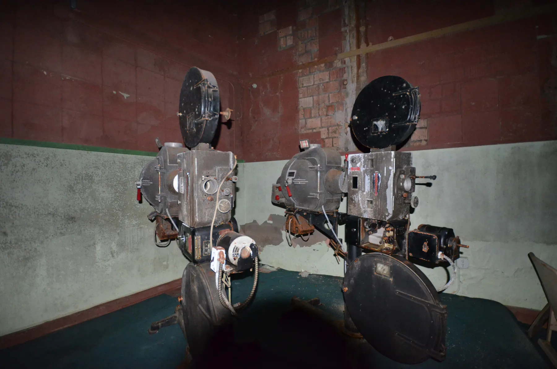 Two vintage film projectors with large reel housings in the projection booth