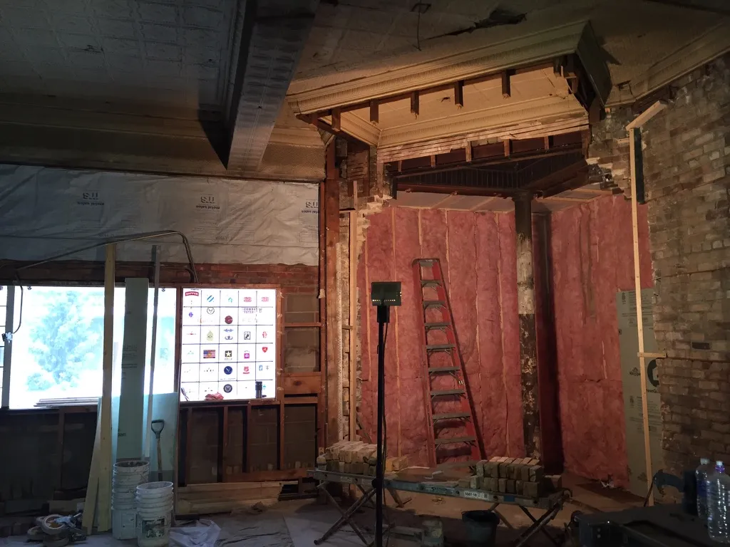 The corner opened up to its framing and brick with insulation and a ladder